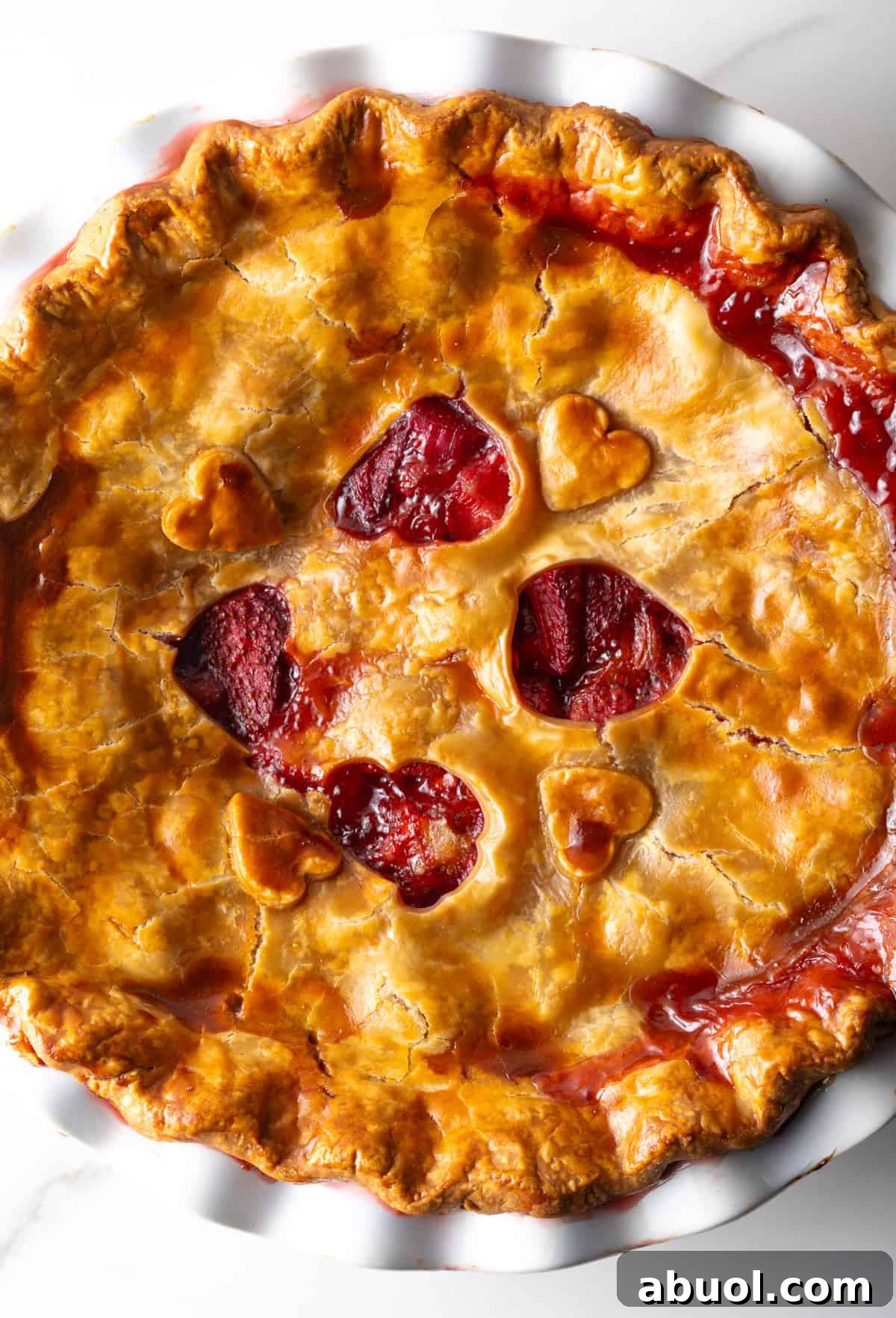 A freshly baked strawberry and rhubarb pie with heart shapes cut in the center of the pie.
