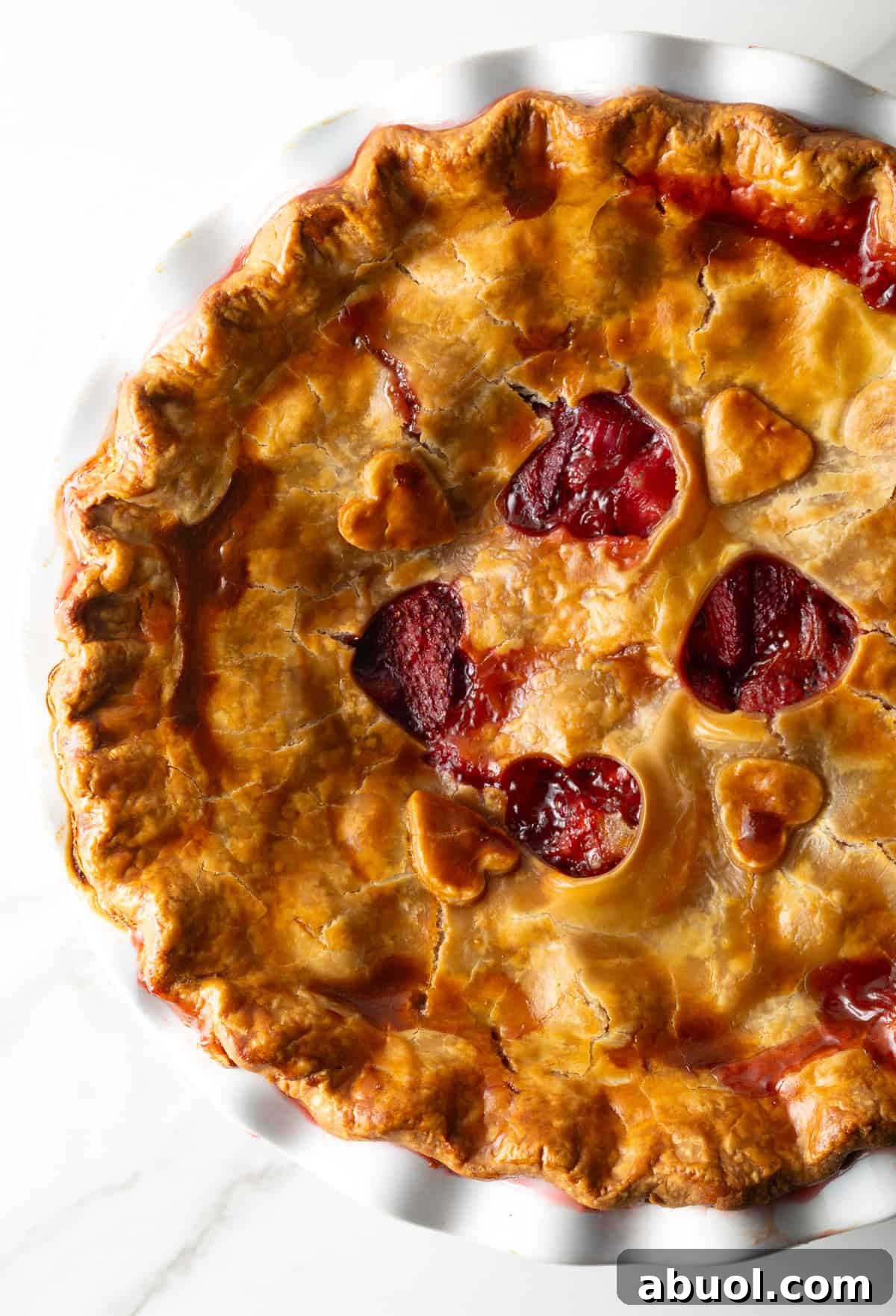 A freshly baked homemade strawberry rhubarb pie with heart shapes cut in the center of the pie.