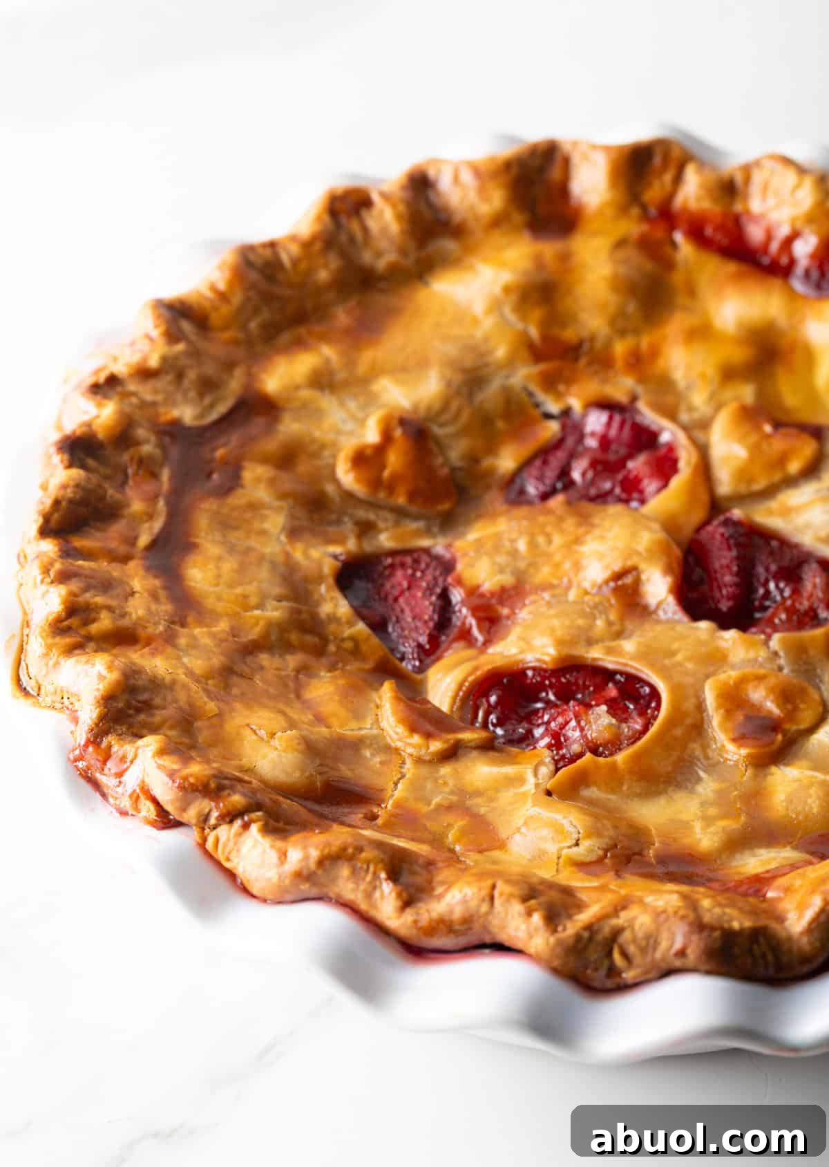 A full rhubarb strawberry pie with heart shapes cut in the center of the pie.