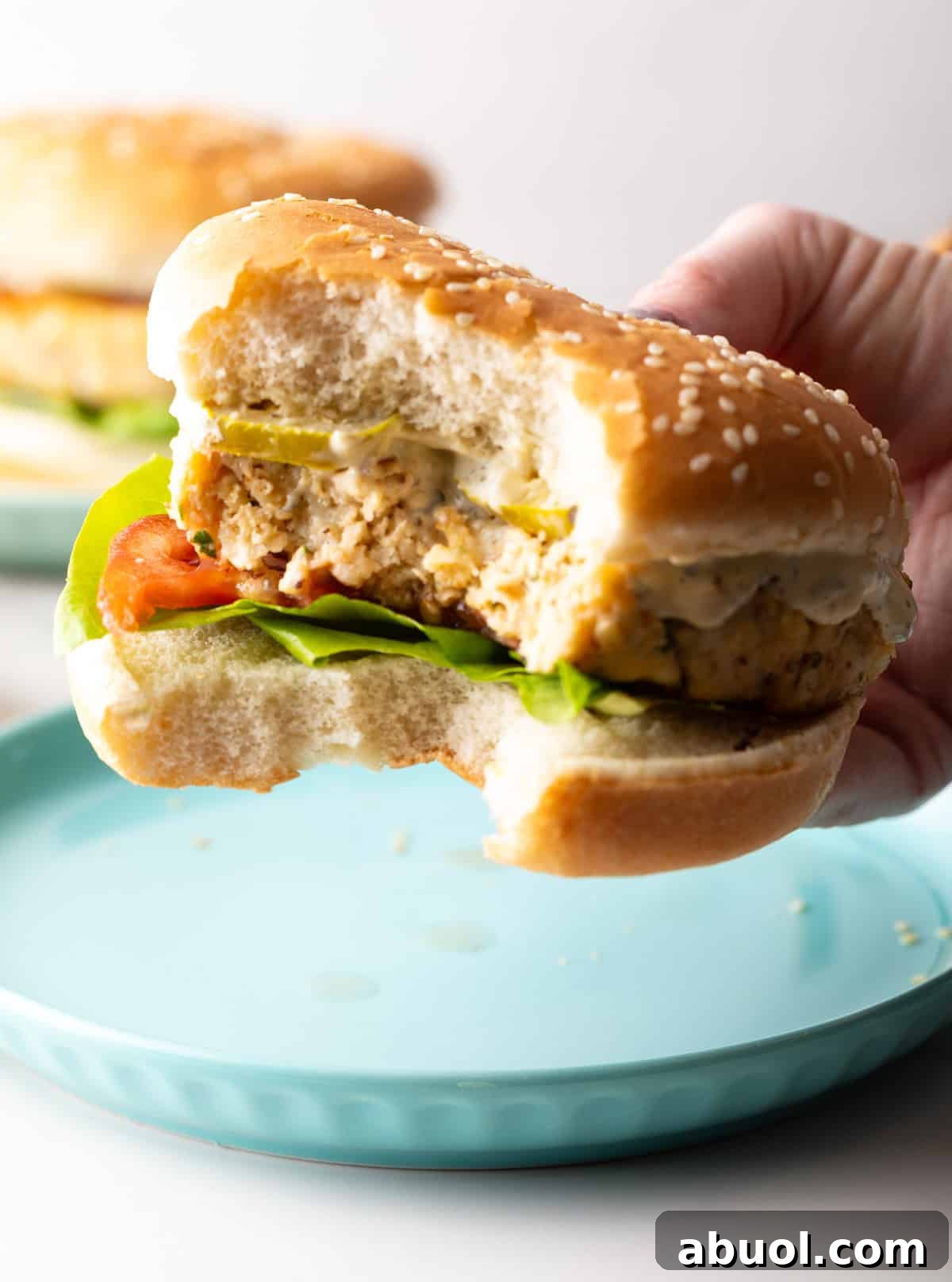 A hand is holding a recipe for fish hamburgers with a bite taken out.
