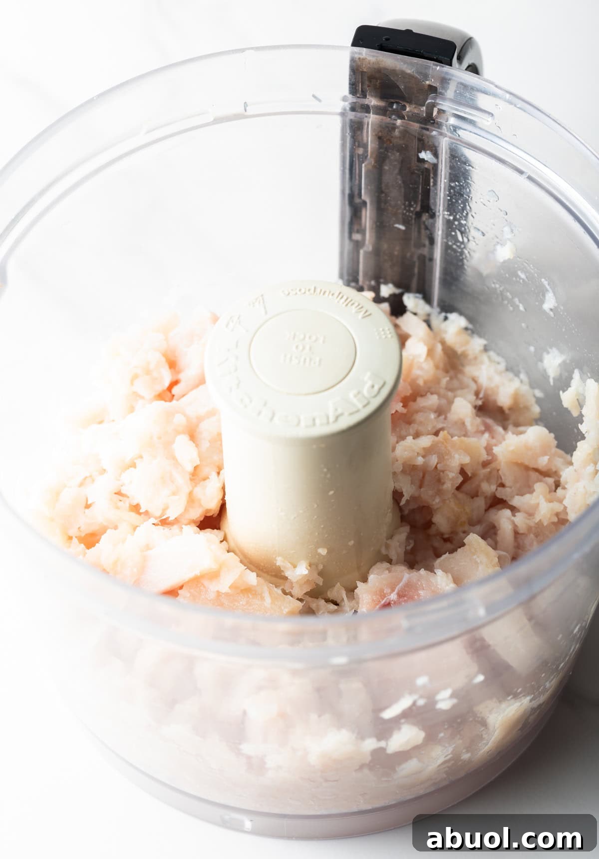 Raw fish is being pulsed in a food processor to make fish patties.