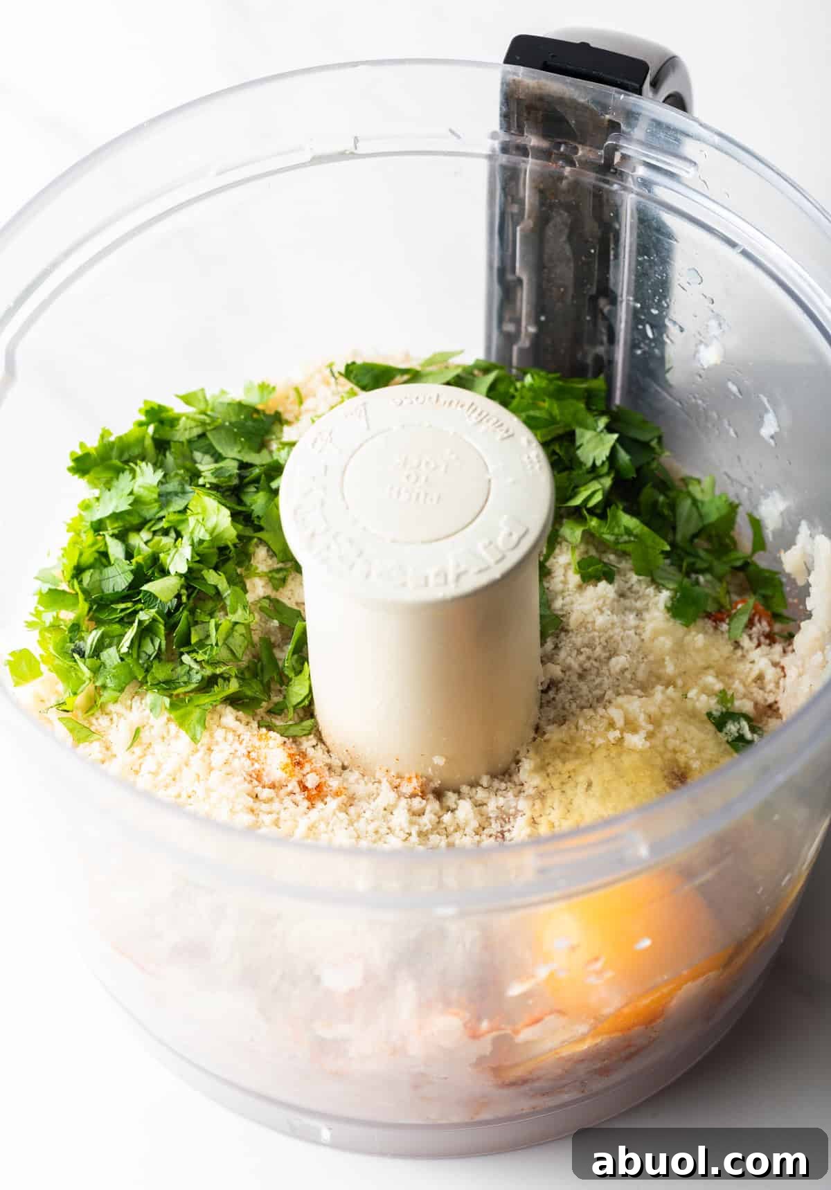 Egg, mayonnaise, and seasonings are being added to a food processor with white fish.