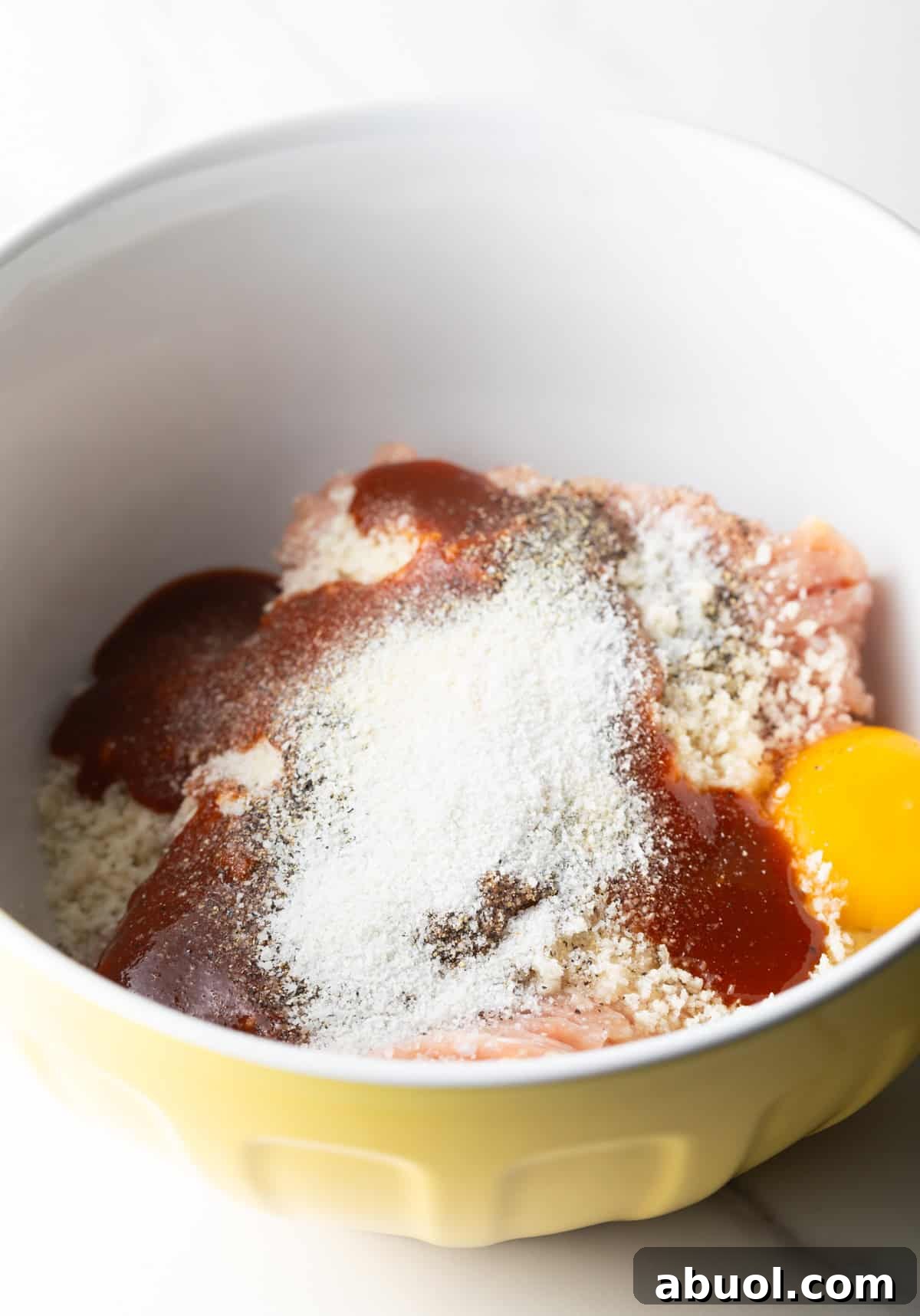 A bbq chicken burgers mixture sitting in a white bowl ready to be mixed together.