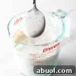 ranch dressing recipe made in a pyrex pitcher with spoonful of thick dressing