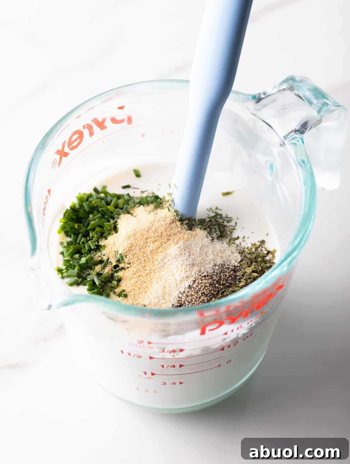 A buttermilk ranch dressing recipe is coming together in a glass measuring pitcher.