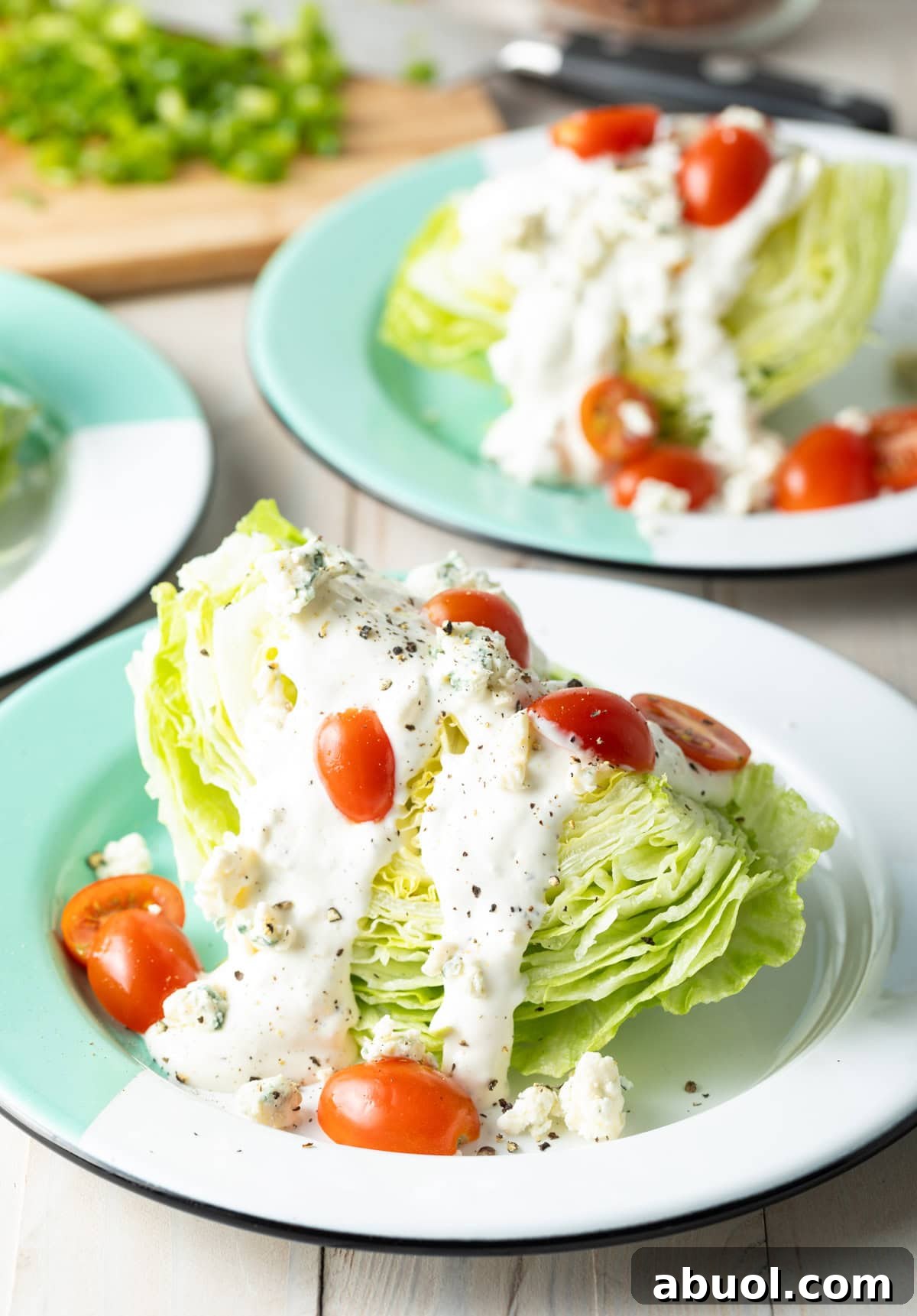 Iceberg lettuce on a plate with blue cheese dressing and halved grape tomatoes.