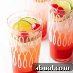 Three glass cups filled with a refreshing cherry limeade recipe, topped with lime wedges and maraschino cherries.