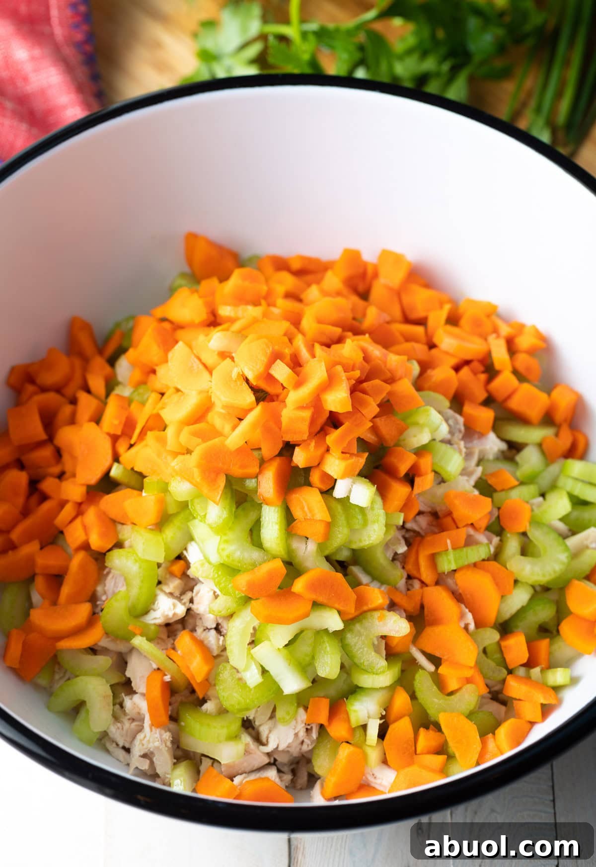 Chopped chicken, celery, and carrots sitting in a bowl being prepped to make a homemade buffalo chicken salad recipe.