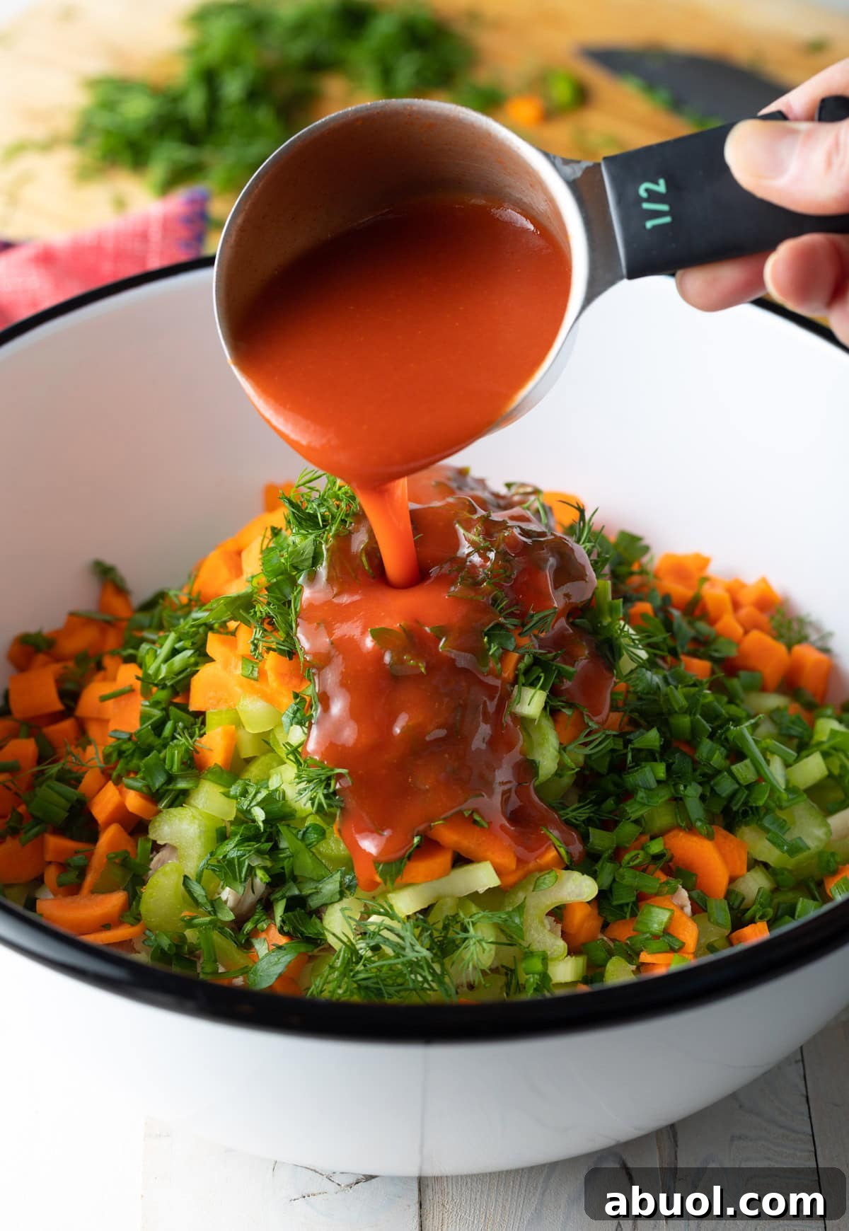 Buffalo sauce is being poured over a low-carb buffalo chicken salad recipe.