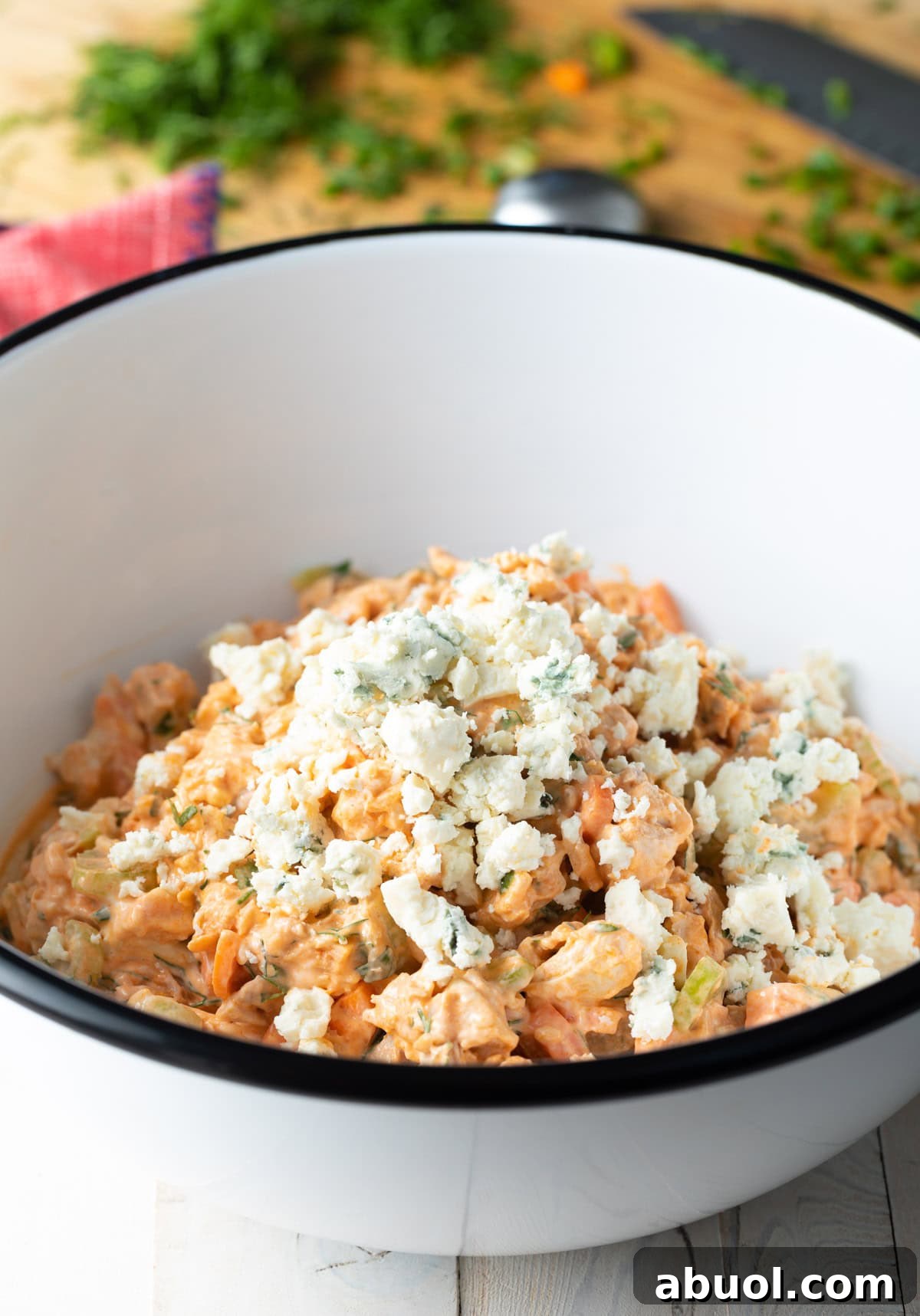 Easy buffalo chicken salad topped with blue cheese crumbles, sitting in a white bowl.