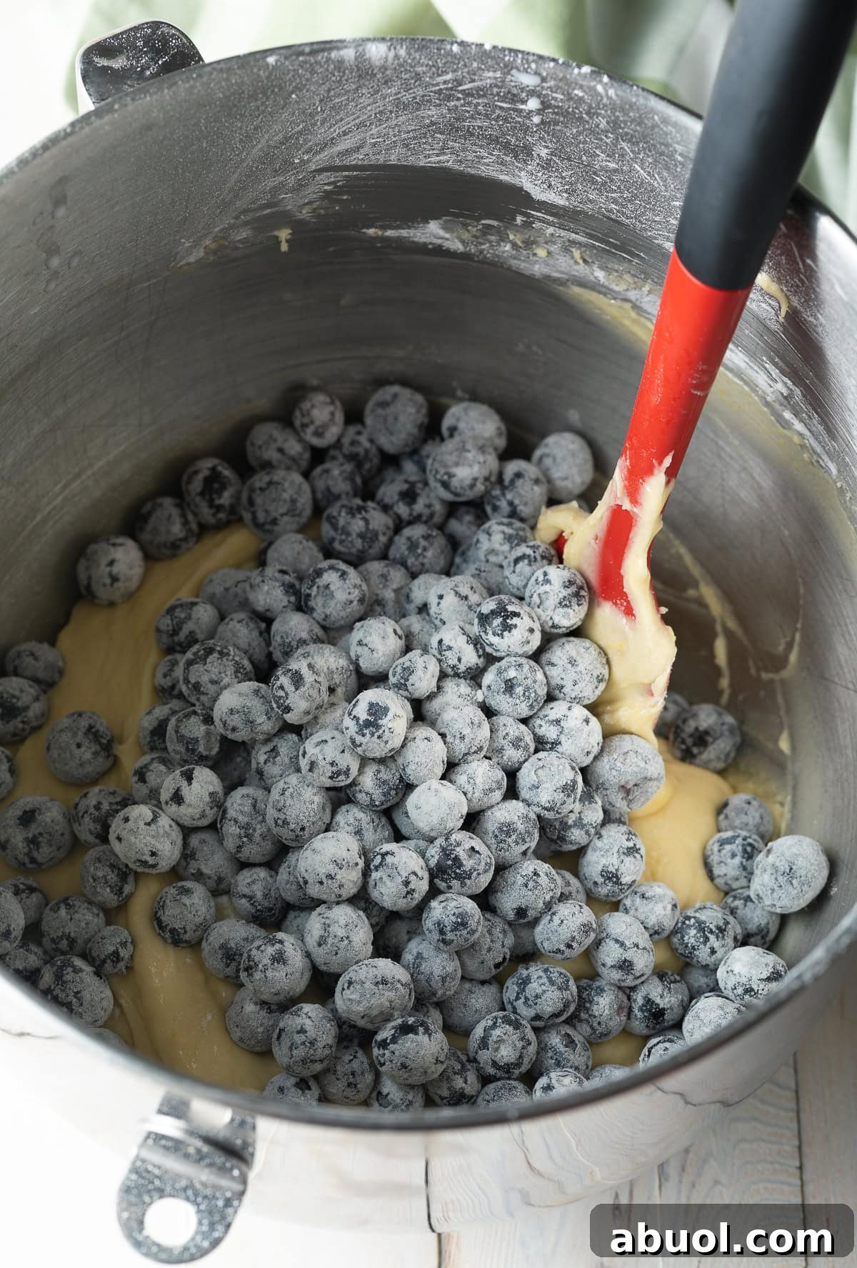 Blueberries are being added to a blueberry muffin recipe mixture.