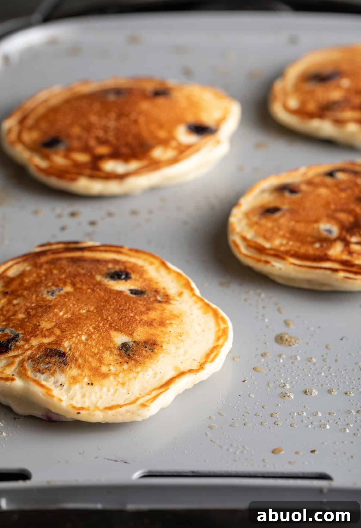 4 cooked blueberry pancakes on a griddle.