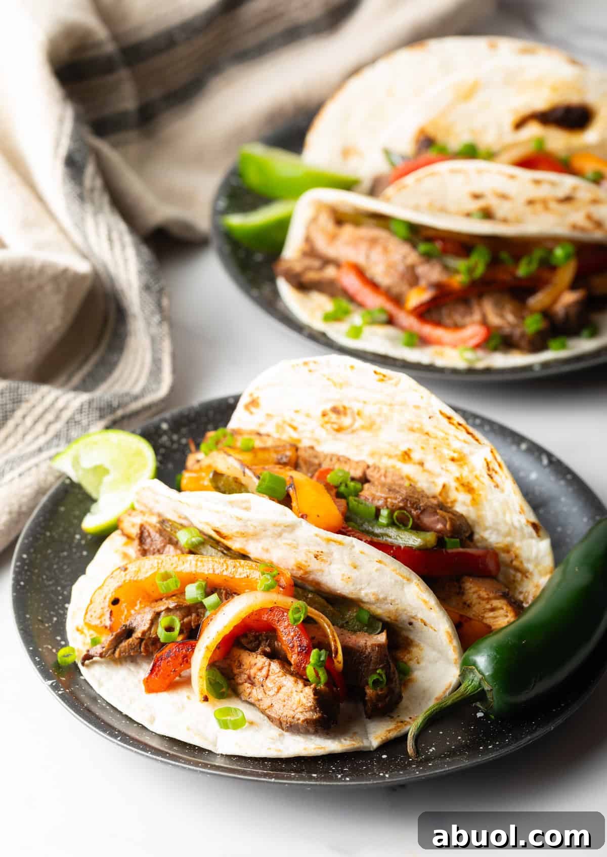 Two tacos on a plate filled with a steak fajita mixture using a steak fajita marinade.