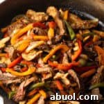 A black skillet filled with steak and pepper fajitas using a homemade fajita marinade.