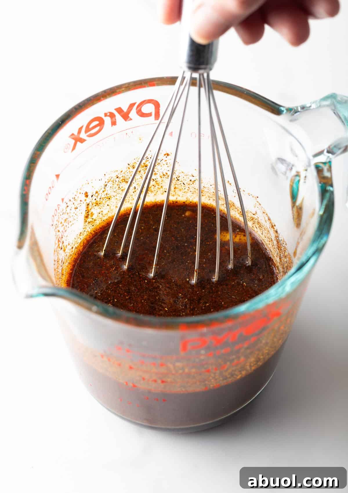 An easy fajita marinade is being whisked in a glass measuring cup.
