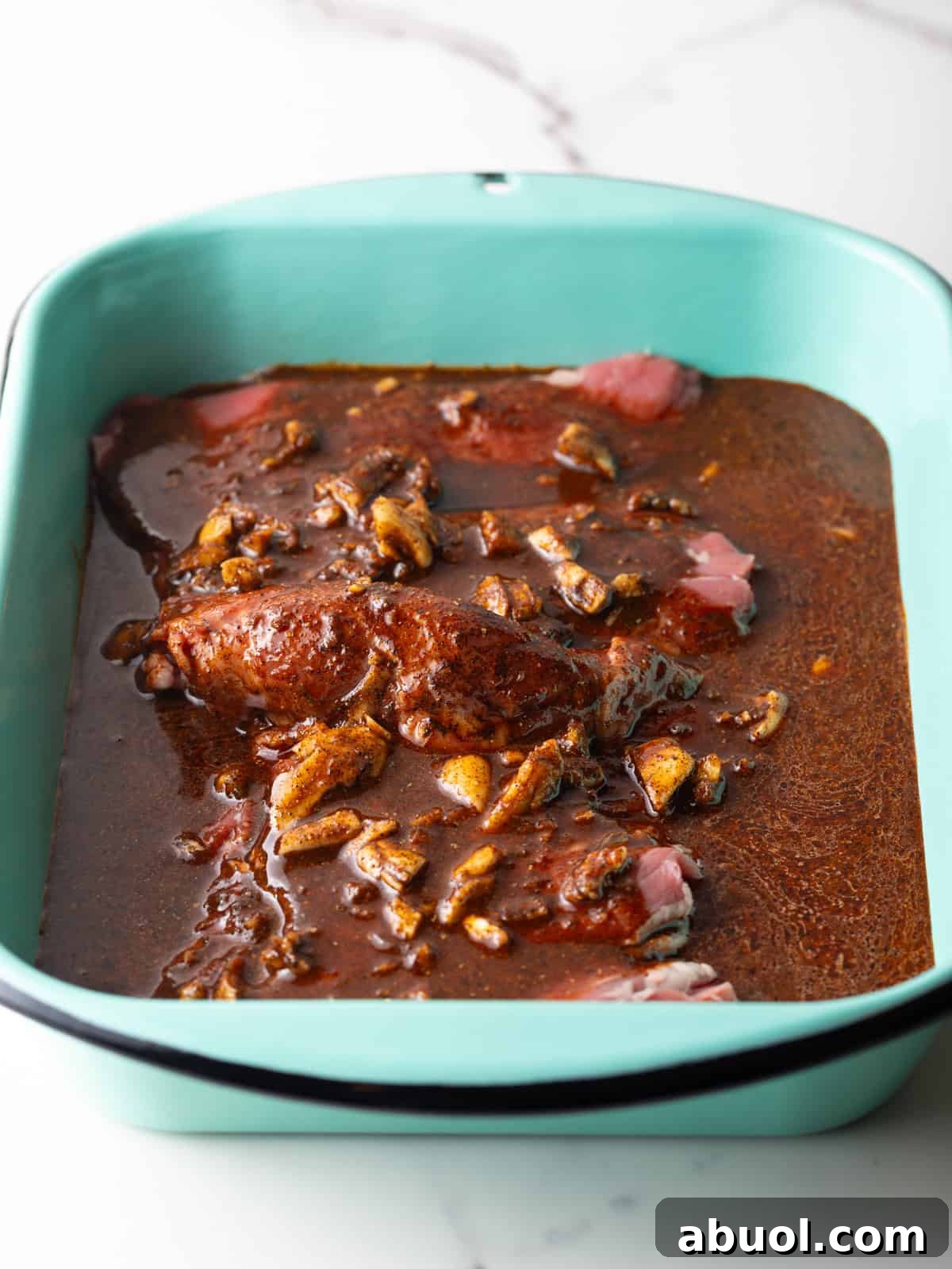 A blue baking dish filled with steak submerged in a fajita marinade.