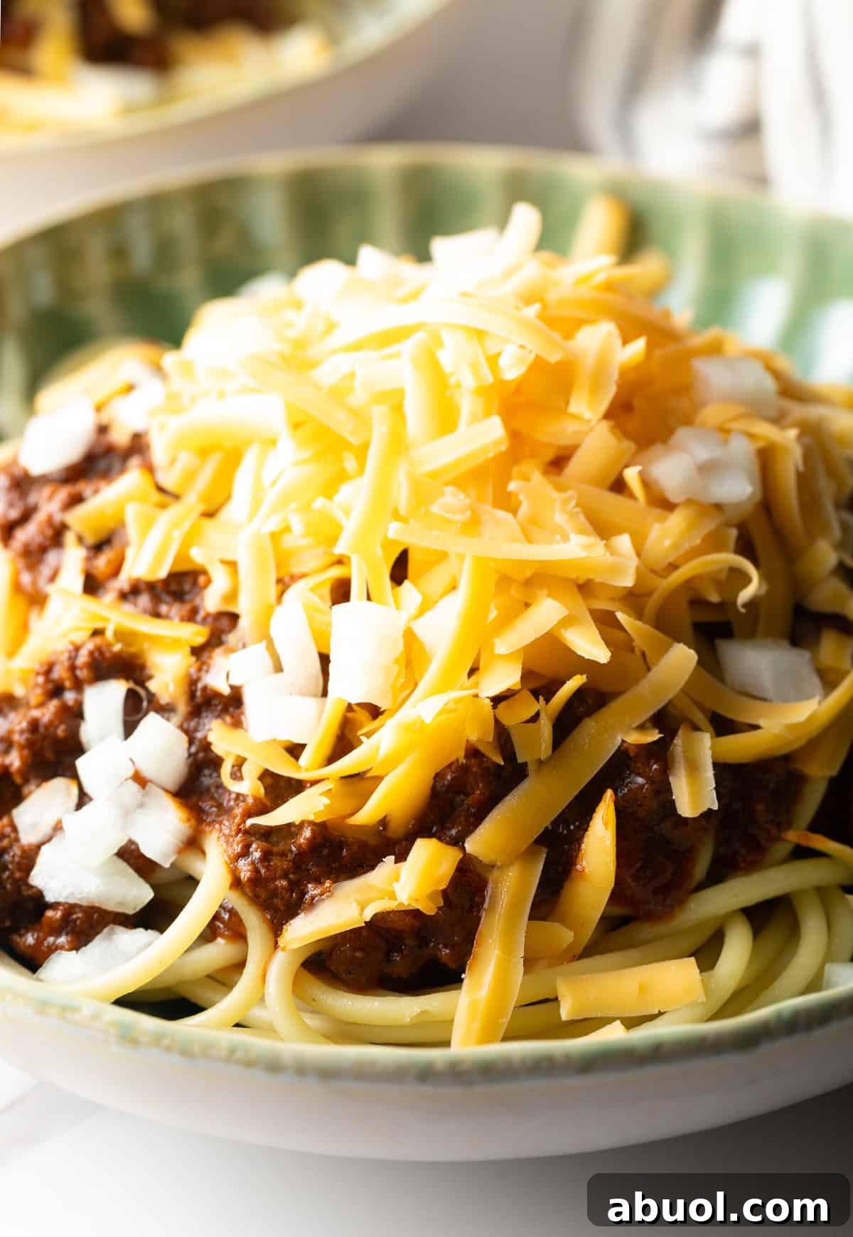 A closeup shot of a classic Cincinnati chili recipe topped with shredded cheese.