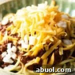 A closeup shot of a classic Cincinnati chili recipe topped with shredded cheese.