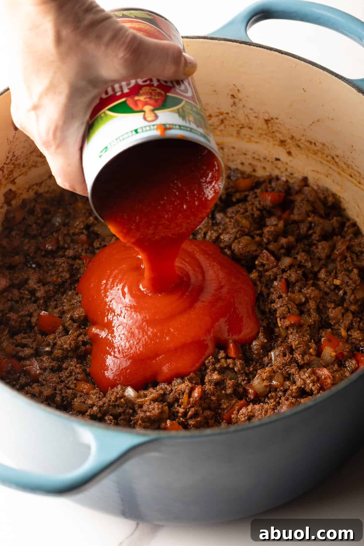 Tomato sauce is being added to a skyline chili recipe.