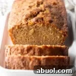 An apple bread recipe on a white dish with two slices cut in front of the loaf.